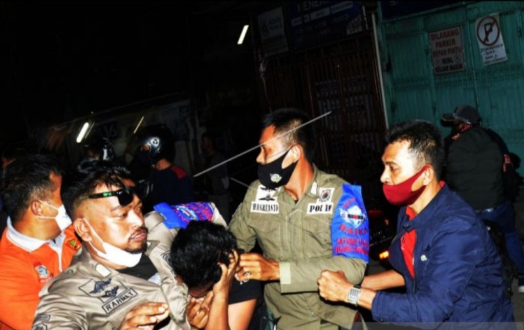 Petugas gabungan mengamankan pemilik rumah makan karena melawan petugas saat patroli pembatasan jam operasional di Anjungan Pantai Losari Makassar, Sulawesi Selatan, Jumat (11/6/2021) malam (Foto: Antara/Abriawan Abhe)