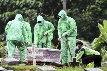 Ilustrasi. Petugas pemakaman menurunkan peti jenazah pasien covid-19 di TPU Pondok Ranggon, Jakarta.