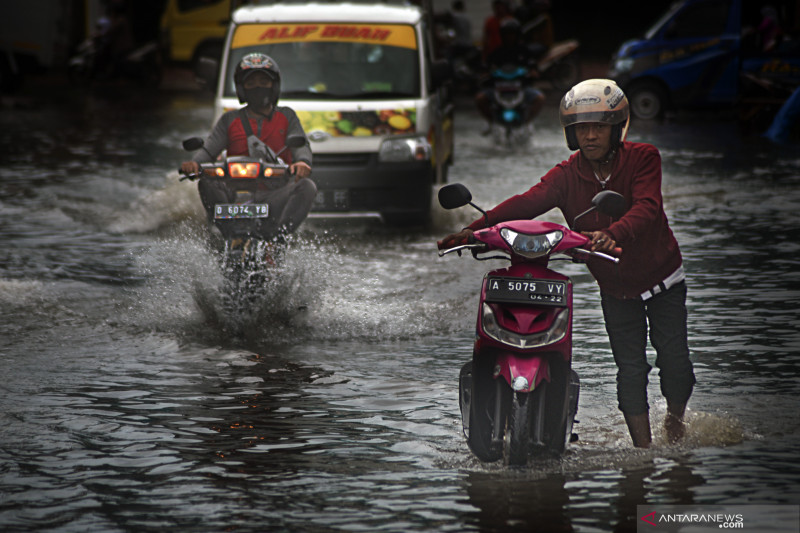 Ilustrasi--Warga mendorong sepeda motor melintasi genangan banjir di kawasan Pasar Induk Rau, Serang, Banten. (Foto: ANTARA/Fathul Rahman)
