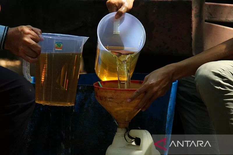 Dua pekerja menuangkan minyak goreng ke wadah milik warga saat giat pasar murah minyak goreng curah di kawasan Jalan Ujungpandang, Pontianak, Kalimantan Barat. Foto: Antara/Jessica Helena Wuysang/aww/pri