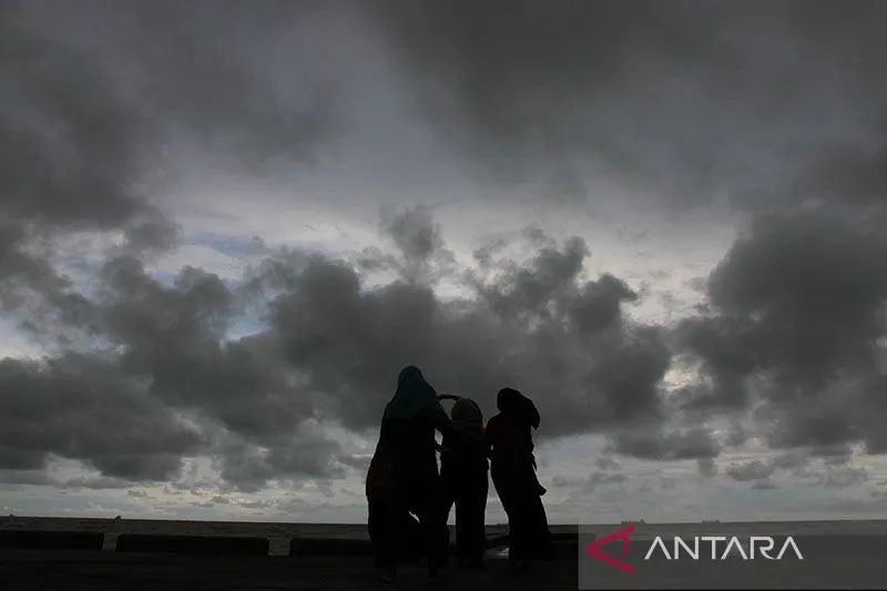 Sejumlah warga berada di kawasan pantai yang di selimuti mendung hitam di Johan Pahlawan, Aceh Barat, Jumat, 26 April 2019. Foto: Antara/Syifa Yulinnas/pd/pri.