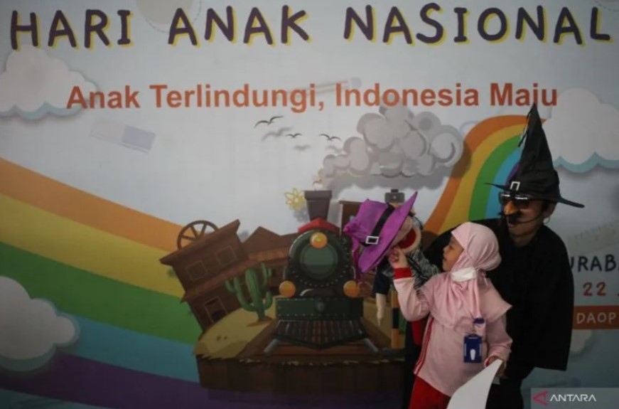 Seorang anak berpose dengan pendongen Kak Haris (kanan) usai mengikuti lomba mewarna di Stasiun Gubeng Surabaya, Jawa Timur, Jumat (22/7/2022). PT Kereta Api Indonesia (Persero) Daerah Operasi 8 Surabaya menggelar lomba mewarna yang diikuti sejumlah anak 