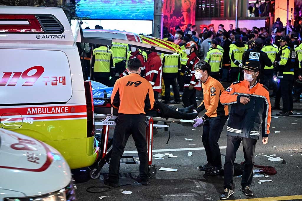 Petugas mengangkut korban luka ke ambulans di lokasi tragedi Itaewon, Seoul, Korea Selatan, 29 Oktober 2022. (AFP PHOTO)