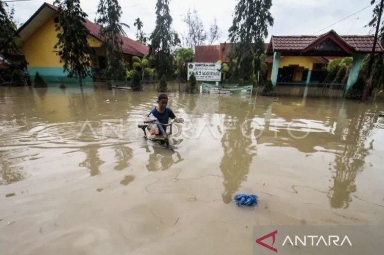 Arsip. Visual seorang anak menuntut sepedanya di tengah banjir yang melanda Kecamatan Matang Kuli, Aceh Utara, Aceh, Senin (23/1/2023). (ANTARA FOTO/Rahmad)